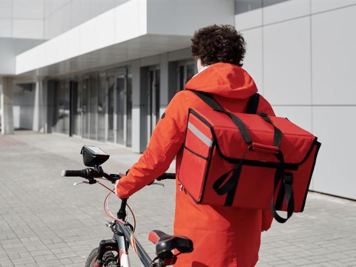 Livreur à vélo avec son sac isotherme rouge (photo d’illustration)
